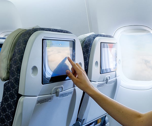 Image of a person using an airline seat touch screen.