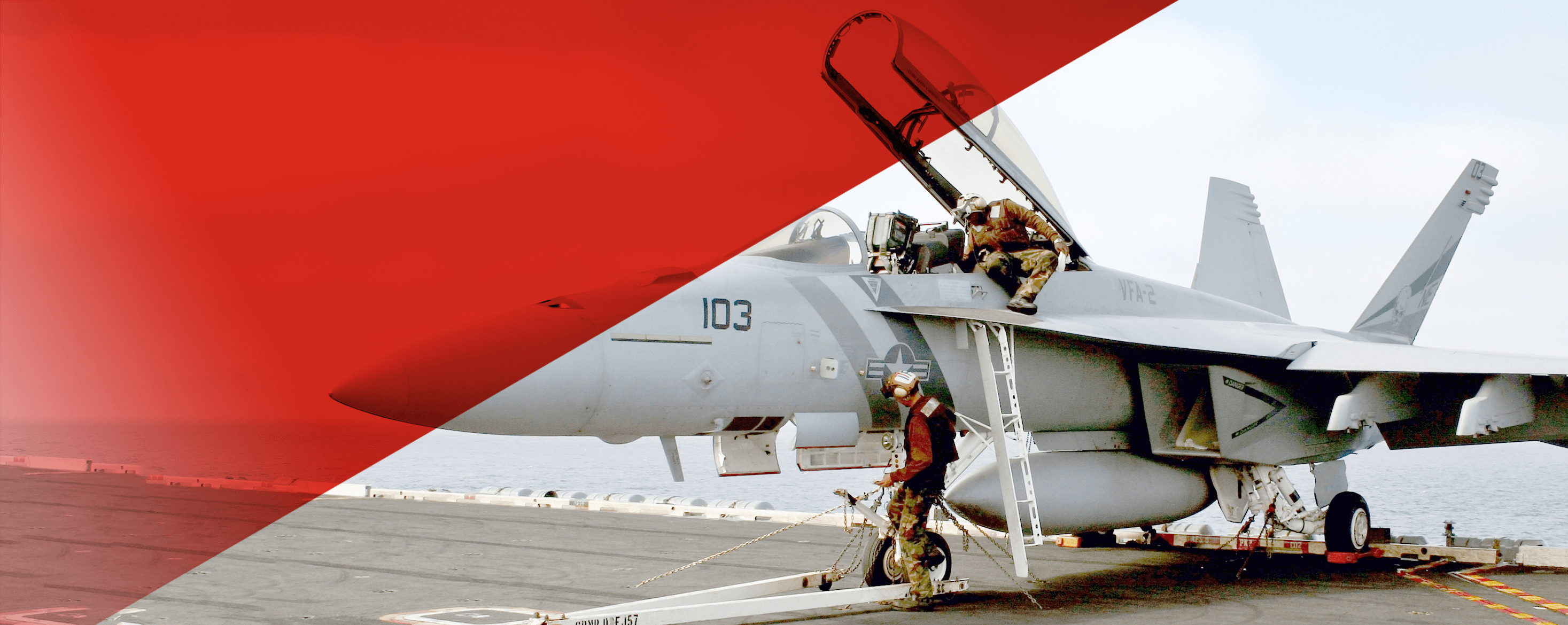 Crew doing maintenance on a plane on an aircraft carrier. 