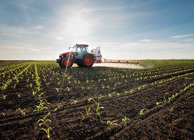 Image of a tractor spreading biostimulants in the field during daytime.