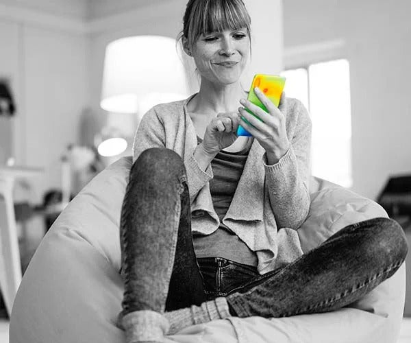 A monochrome photo of a woman using a smartphone. Thermal imaging highlights that there are no hotspots on the phone, thanks to GORE® Thermal Insulation.