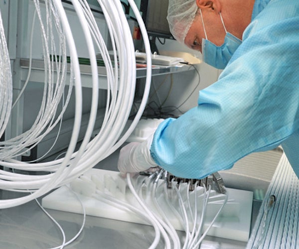 Engineer in cleanroom gear tests the electrical performance of every element of a Gore cable.