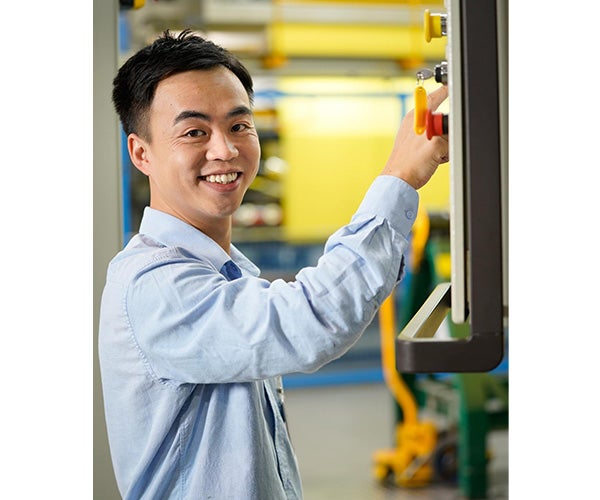 An Associate standing at a machine smiling