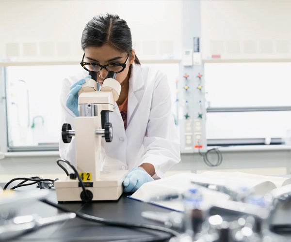 A scientist looking through a microscope.