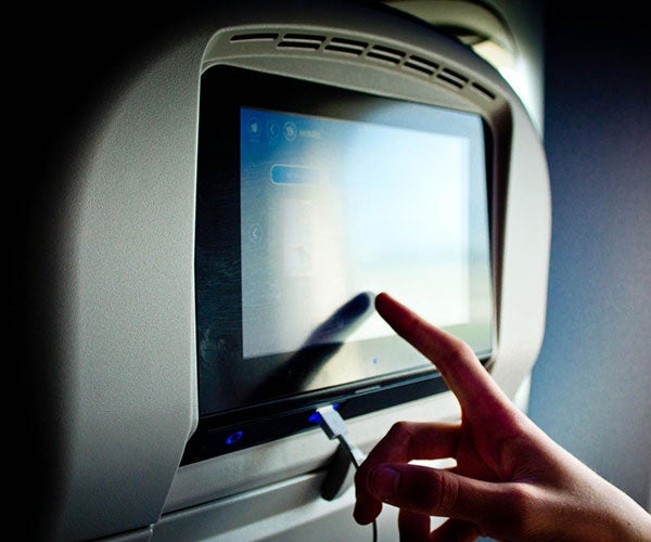 Hand touching screen on airplane seat