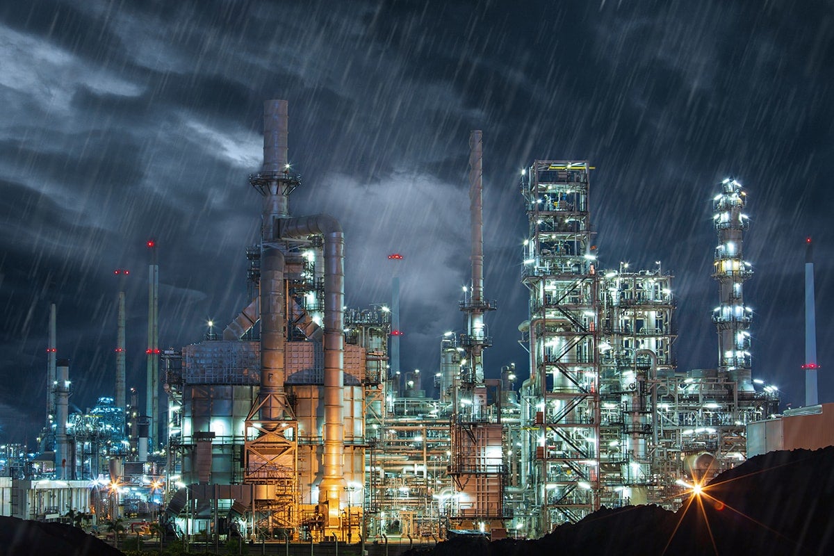 A processing plant at night while it's raining.