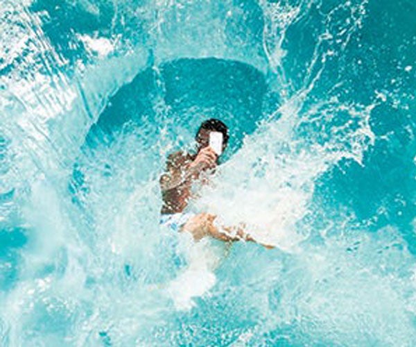 Surfer looking at phone in ocean water