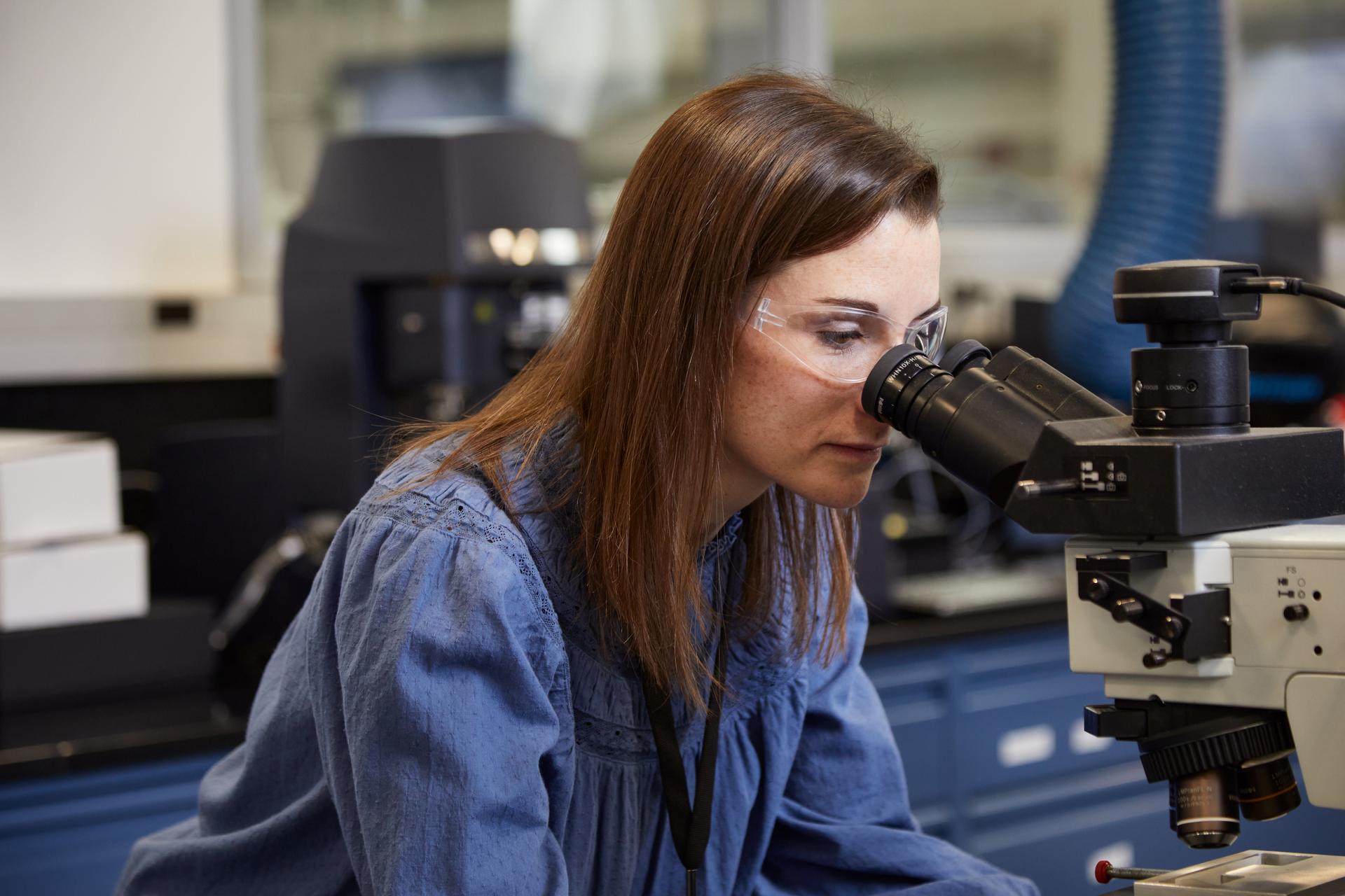 associate looking in a microscope in a plant setting