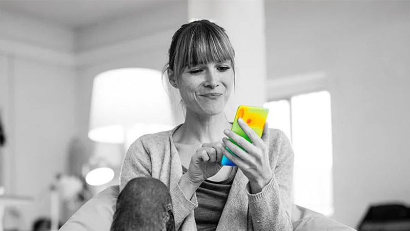 Woman smiling while using a heat-mapped smartphone illustrating device thermal imaging