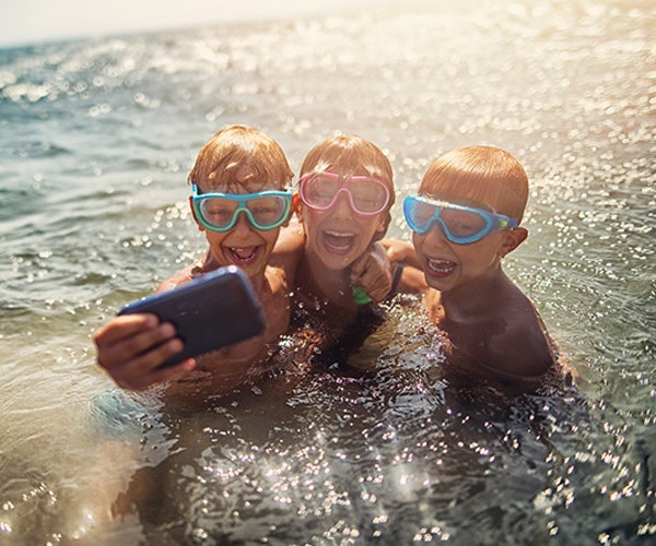 kids in water with goggles and a phone