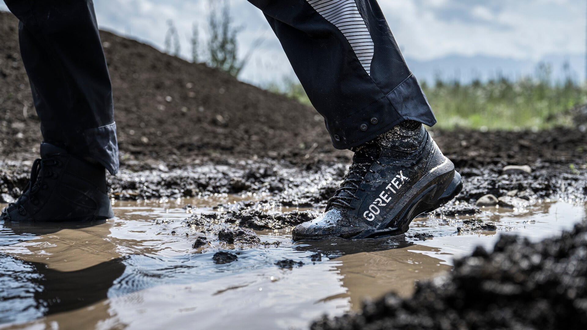 close up of GORE-TEX boots walking through muddy terrain