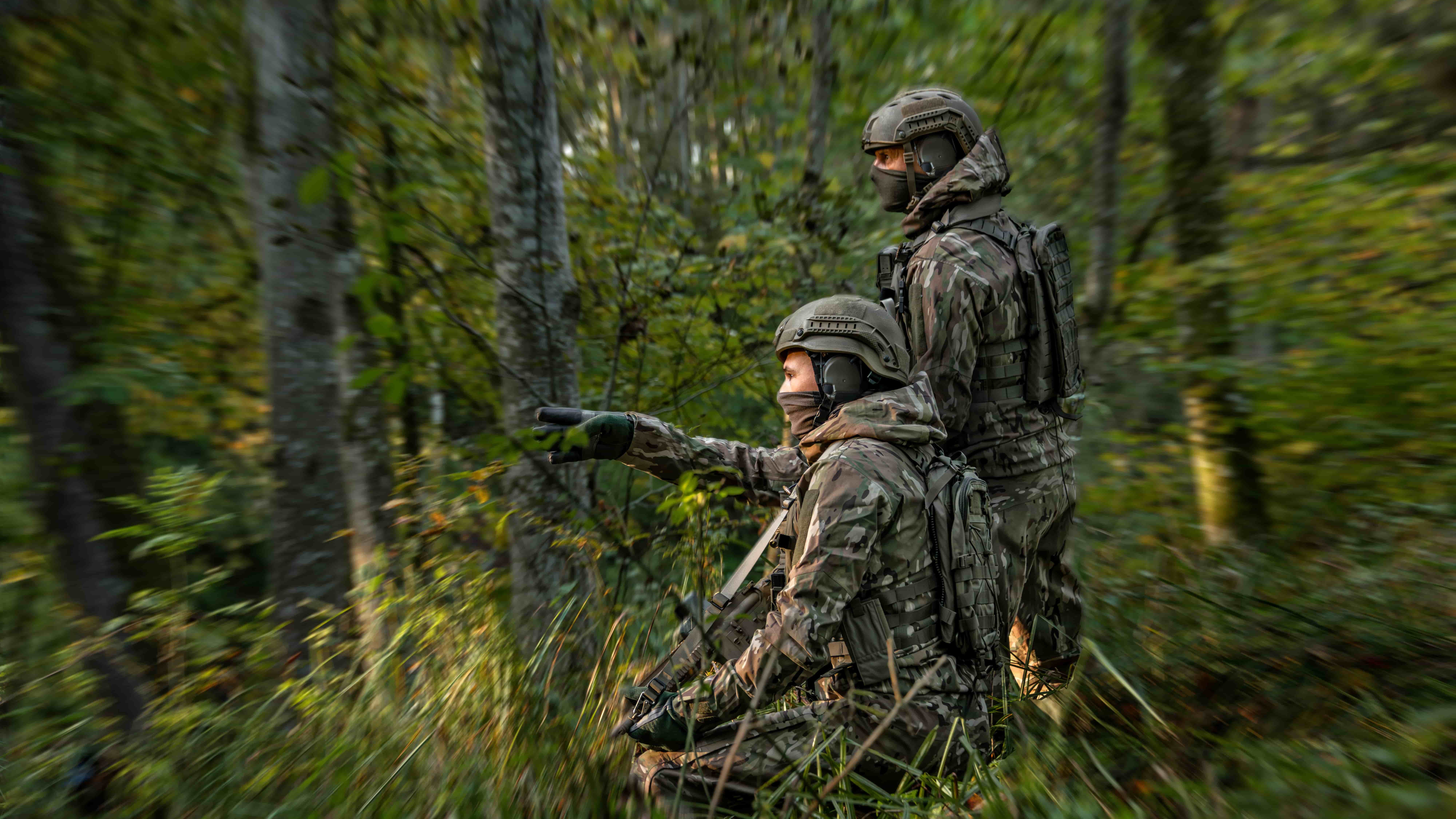 two people in camouflage military gear in the woods