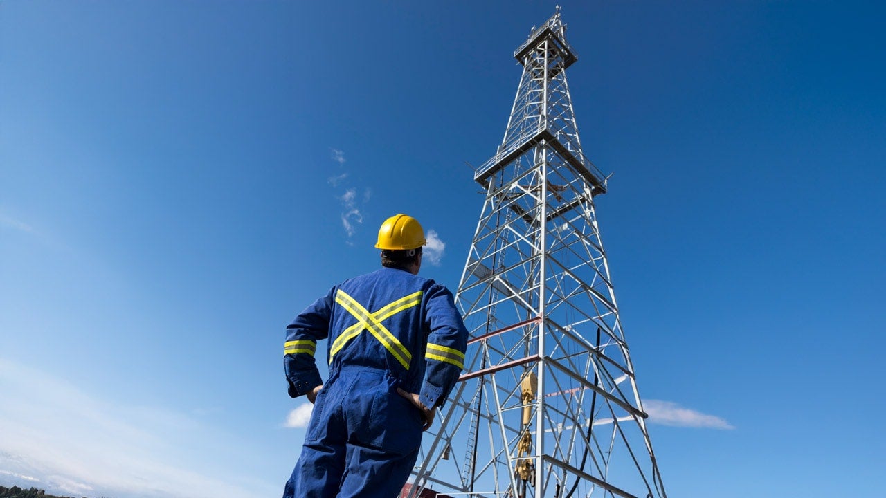 Oil Rig worker wearing protective gear looking at the sky.