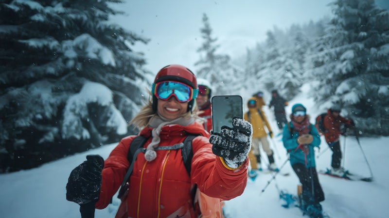 Woman holding a mobile device while walking on a snowy trail