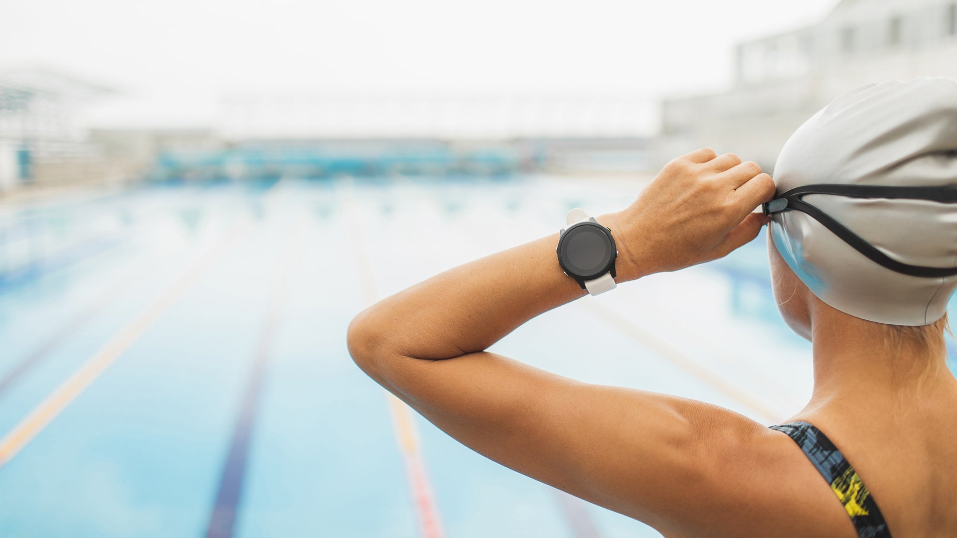 swimmer putting goggles on with smartwatch on her wrist