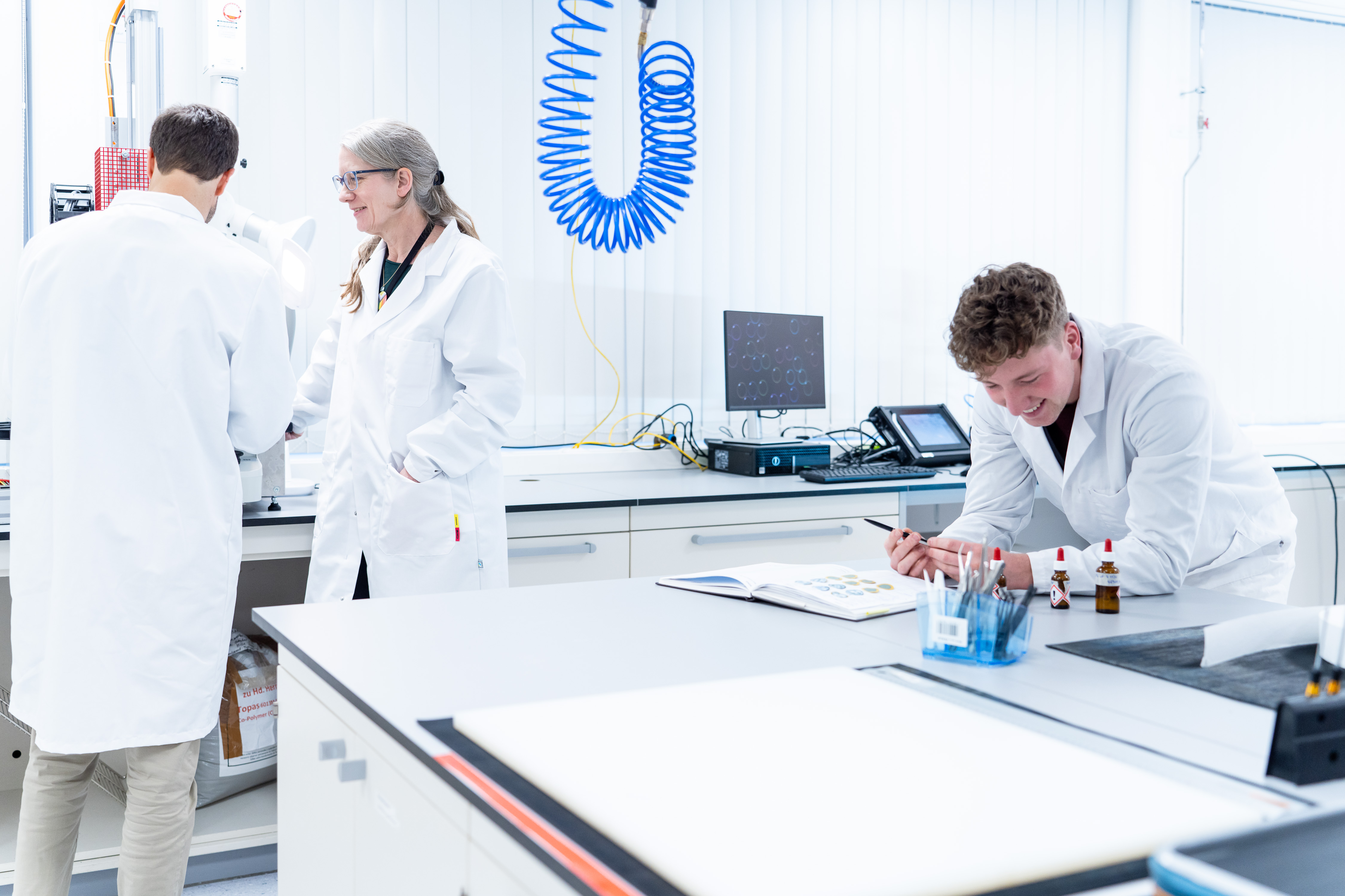 Associates in white lab coats working together in a bright laboratory with equipment and samples