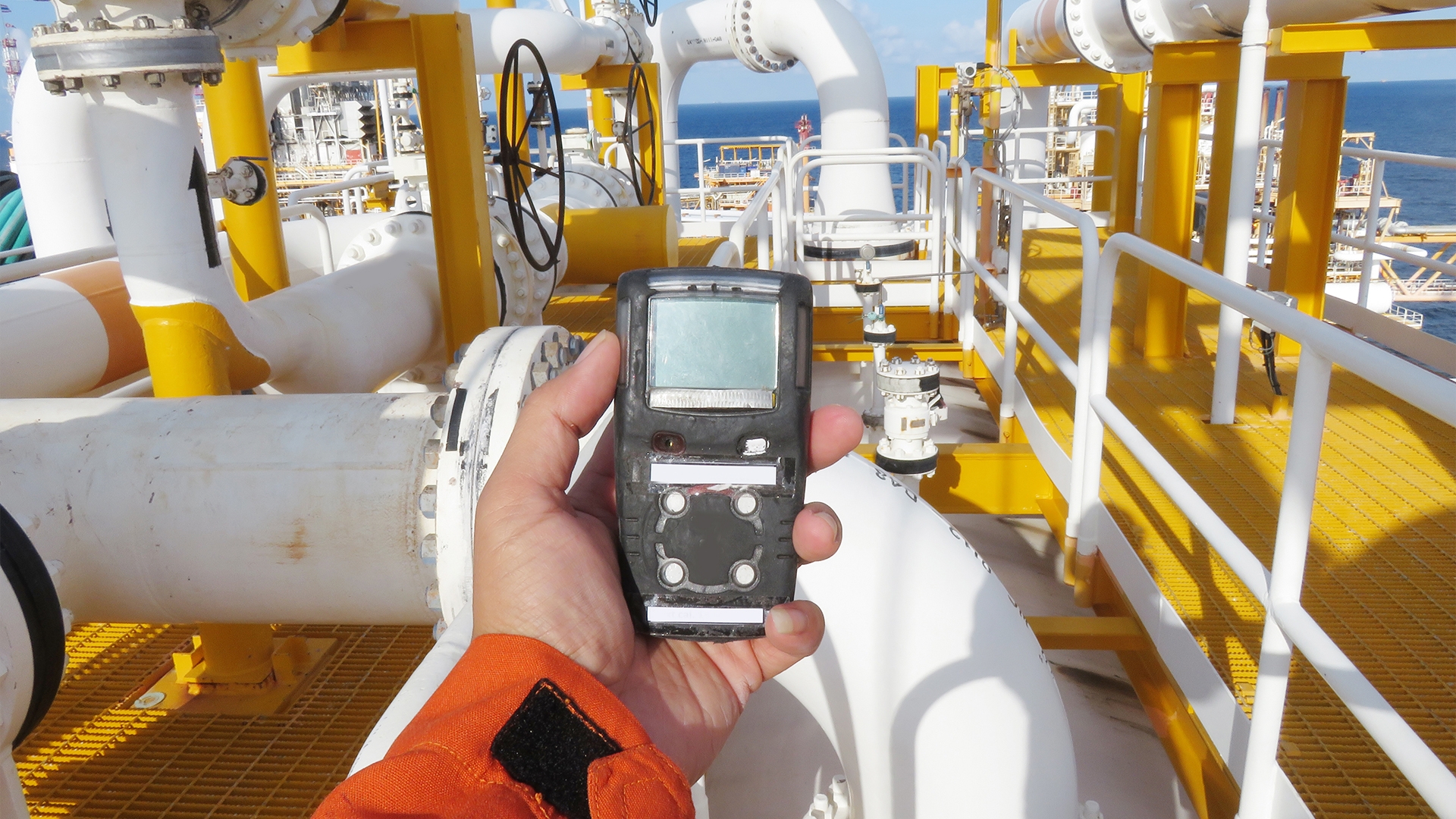 Hand holding H2S gas sensor on offshore platform