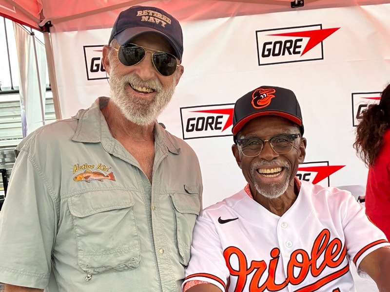 Al Bumbry smiles beside a fair attendee for a photo inside the Gore booth, with Gore-branded backdrop panels behind them.