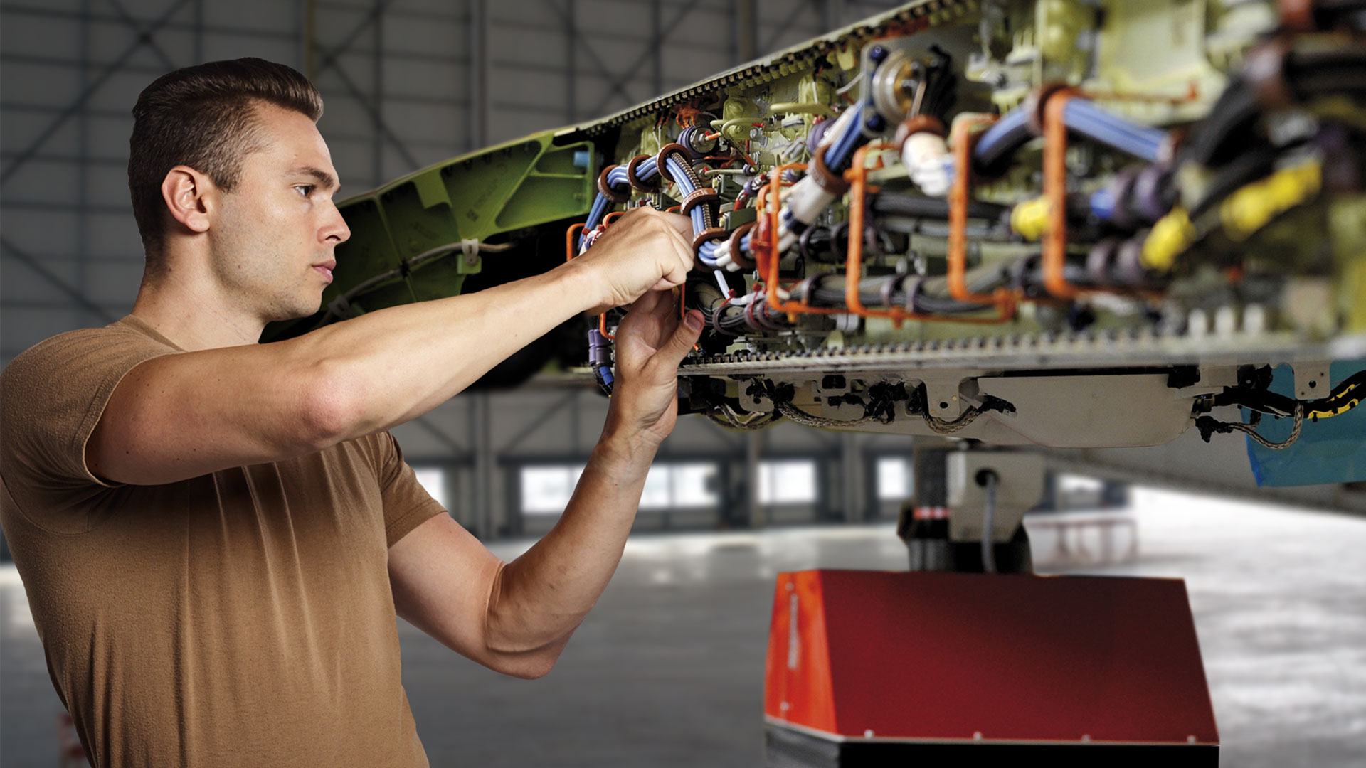 Military technician performing maintenance on a fixed-wing aircraft.