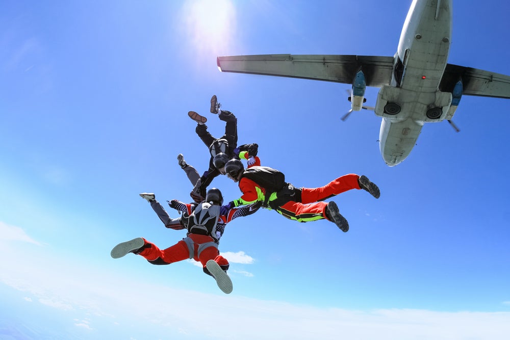 Three skydivers leaving a plane in formation.