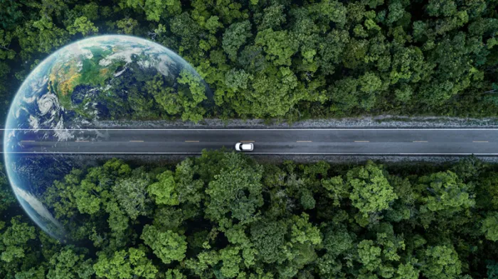 Car driving on a road between a green foliage. A stylistic earth is added on the left.