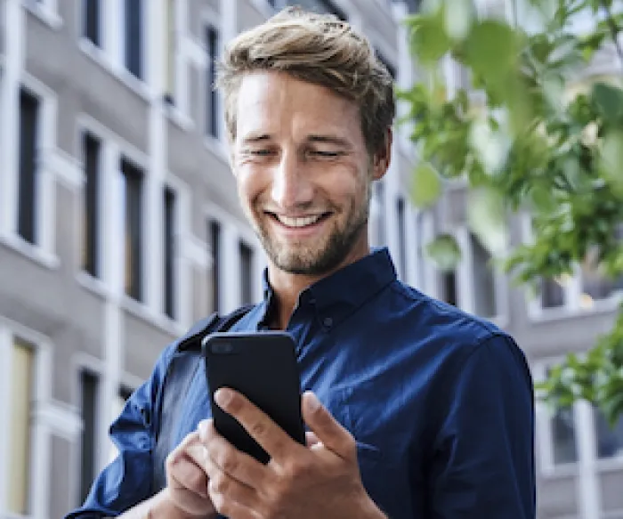 man outside looking at phone and smiling