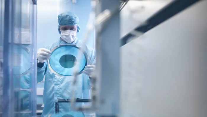 Technician holding a Silicon Wafer in a cleanroom