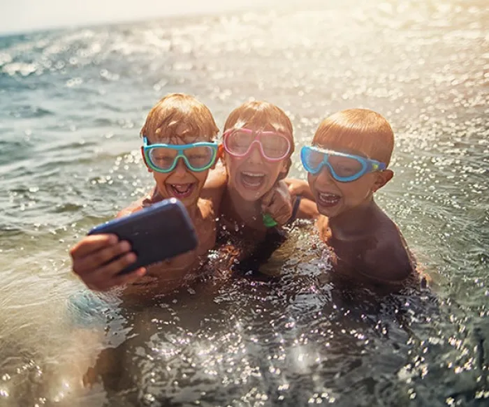 kids in water with goggles and a phone