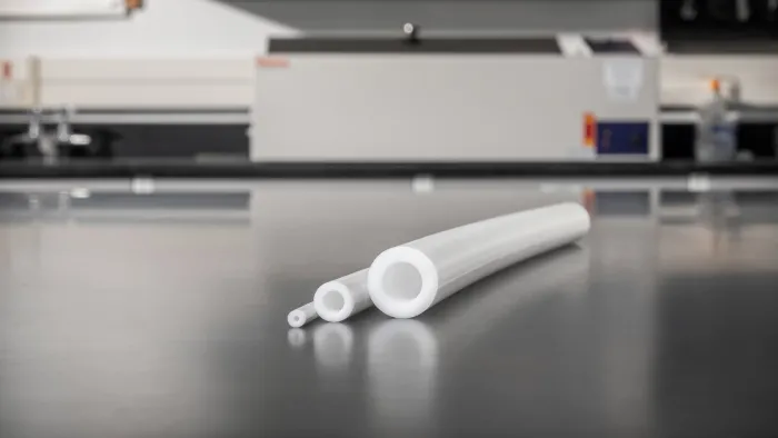 Three white transfer pump tubing sizes displayed on a lab bench with equipment in the background
