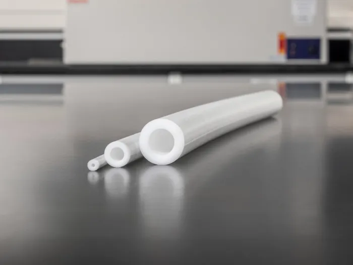 Three white transfer pump tubing sizes displayed on a lab bench with equipment in the background