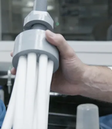 Person holds a multi-tube device used in industrial fluids filtration solutions in a lab setting