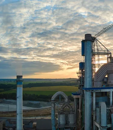Aerial view of cement factory under construction with high concrete plant structure and tower cranes at industrial production area.