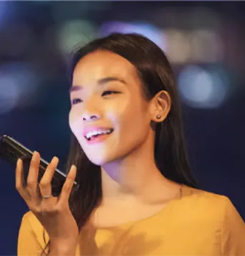Woman wearing yellow smiling while holding a cellphone.