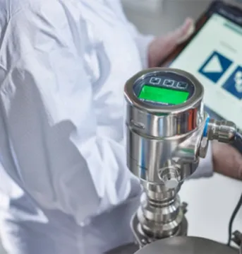 Worker using a specialized device for testing while on a tablet.