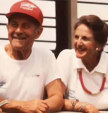 Two people smiling at other person. One person wearing a GORE hat.