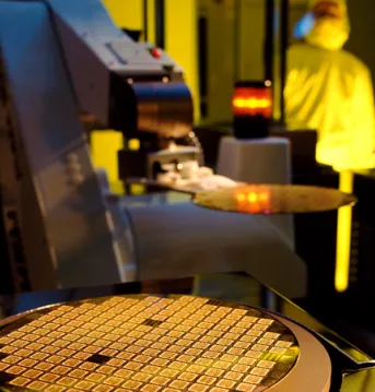 Technician in a cleanroom viewing a microelectronic wafer