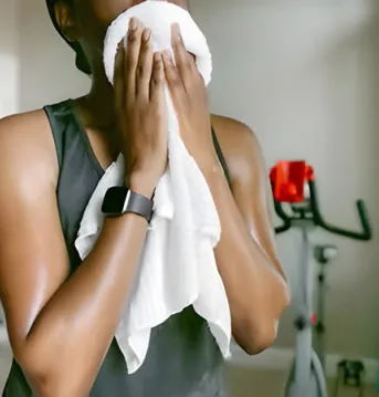 Woman wearing a smartwatch wiping her sweat on a towel.