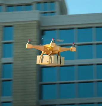 A commercial drone carrying a package through a city.