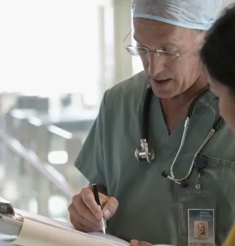 Doctor signing forms in a hospital hallway