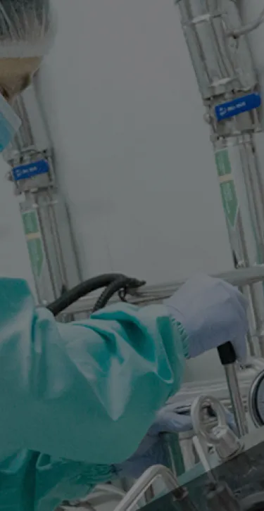 Worker in PPE making adjustments to a specialized machine.