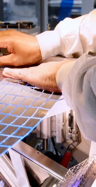 An Associate in cleanroom suit operates on machine for vent production