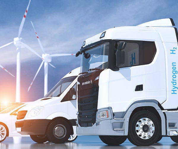Image of white truck, van and car with wind turbines in the background. Truck has "Hydrogen H2" on the side of it. 